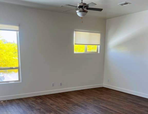 A room with a ceiling fan and a window with blinds.