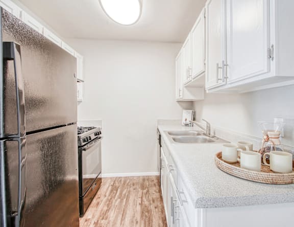 A kitchen with a refrigerator, stove, and sink.