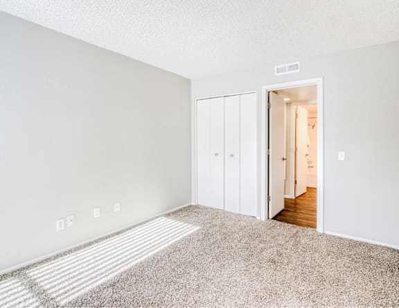 A room with white walls and a carpeted floor with a white door.