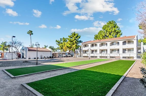 A playground with artificial grass and a building in the background at Tides on East Cactus Apartments, Arizona, 85032