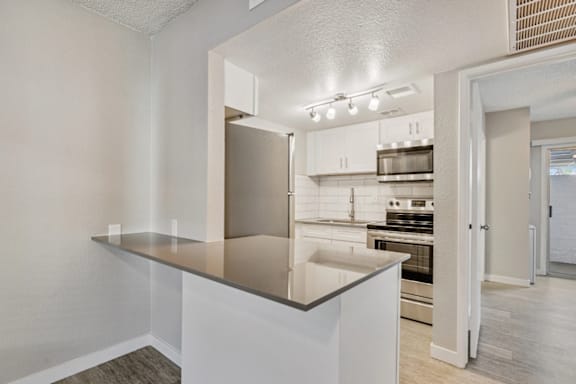 A kitchen with a stainless steel refrigerator and white cabinets.