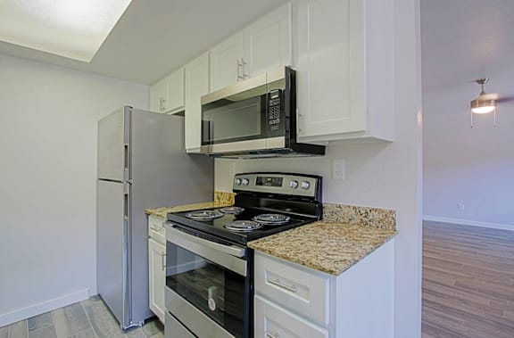 A kitchen with a granite countertop and stainless steel appliances at Aspire Mesa, Mesa, AZ