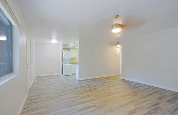 A room with wooden flooring, white walls, and an in-unit, stackable washer and dryer at Aspire Mesa in Mesa, AZ 85210