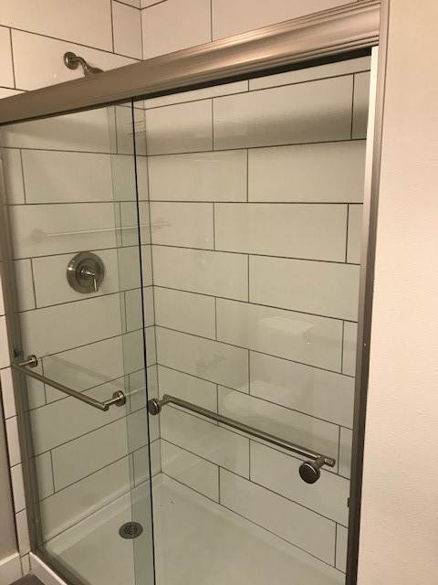 A shower with a glass door and a metal frame.