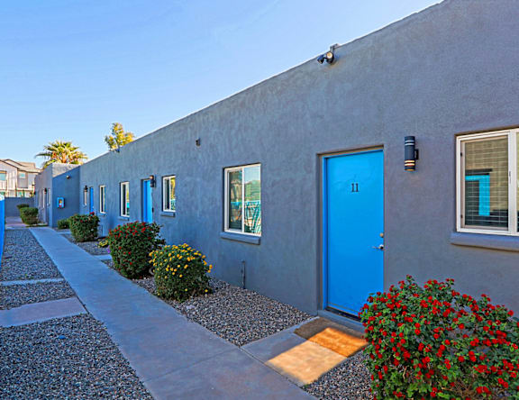 A blue door is on the right side of a grey building.