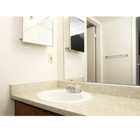 A bathroom sink with a white counter top and a mirror above it.