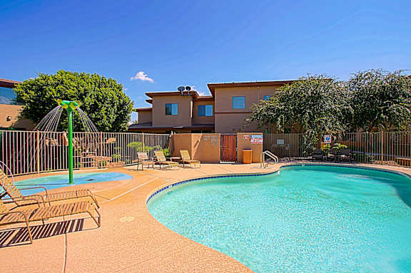 A pool with a slide and chairs in front of a house.
