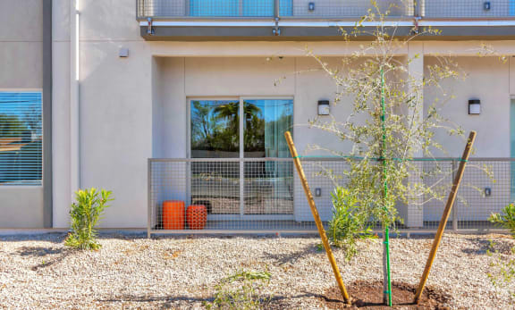 Spacious patio with manicured landscaping, orange ottomans, and outdoor sconce at Allora Phoenix in Phoenix, 85021