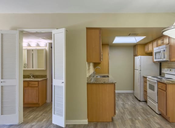 View into Kitchen and Bathroom complete with plank flooring at The Viridian Apartments in Scottsdale, CA