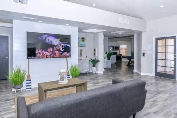 Resident lounge area with a cozy grey couch with a table and television at Tides at Mesa, Mesa, AZ, 85204