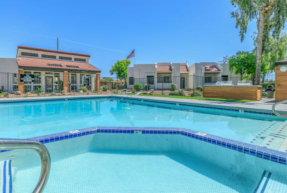 Large swimming pool with soothing spa outlined in dark blue tile at Tides on Southern in Mesa, Arizona
