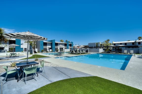 Gorgeous swimming pool area with a patio table and black and white striped umbrella at Connect on Missouri in Arizona 85015