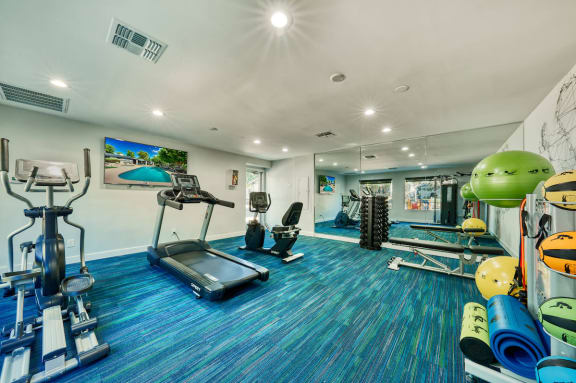Spacious gym with exercise equipment, blue and green carpet, elliptical, and more at Connect on Nothern in Arizona 85301