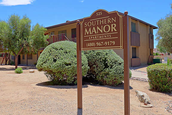 A brown sign that says Southern Manor Apartments in front of a building.