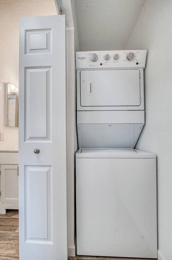 A white washing machine sits in a small space next to a door.