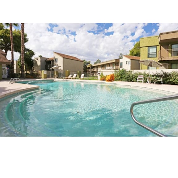 A swimming pool with a metal railing and a sun umbrella.