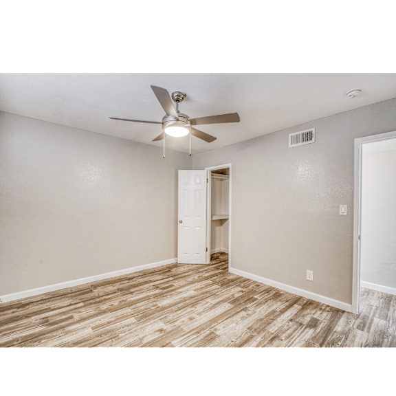 A room with a ceiling fan and a doorway leading to another room.