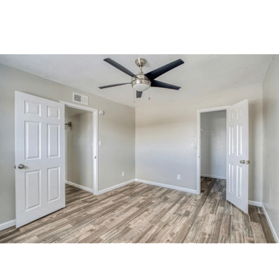 A room with a ceiling fan and wooden flooring.