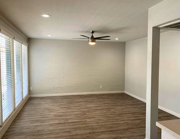 A room with a ceiling fan and wooden flooring.