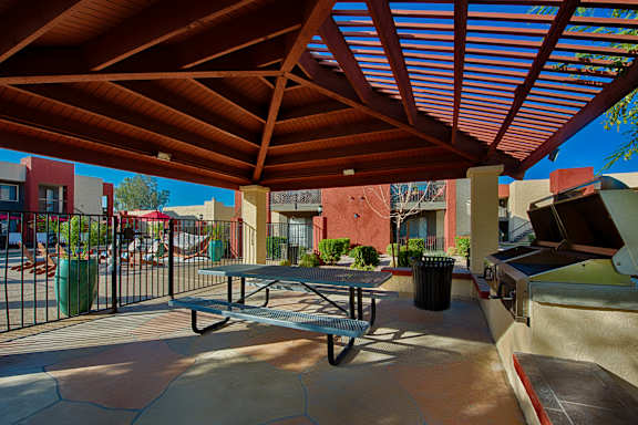 A patio with a table and chairs under a red roof.