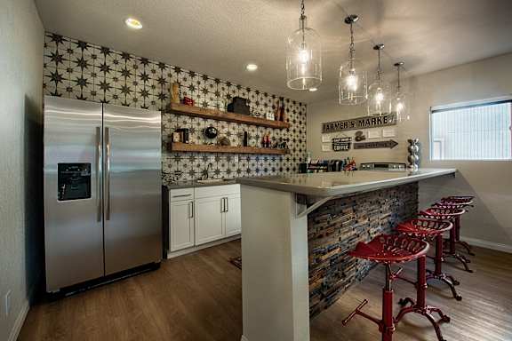 A kitchen with a refrigerator, bar stools, and a patterned wallpaper.