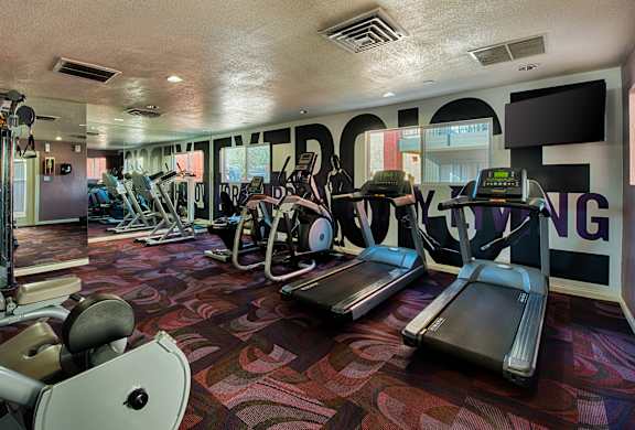 A gym with treadmills, elliptical machines, and other exercise equipment.