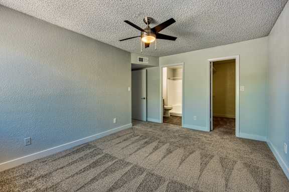 A room with a ceiling fan and carpeted floor.
