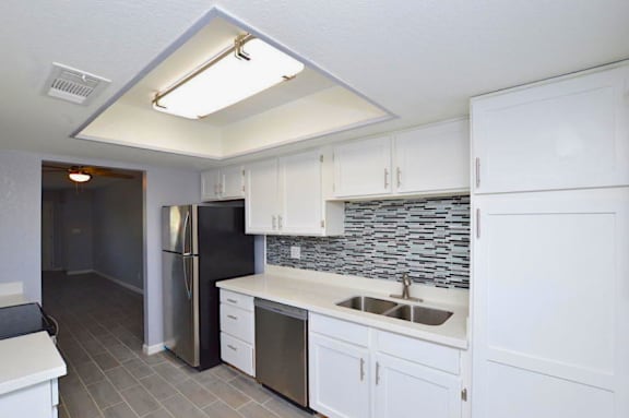 A kitchen with white cabinets and a black fridge.