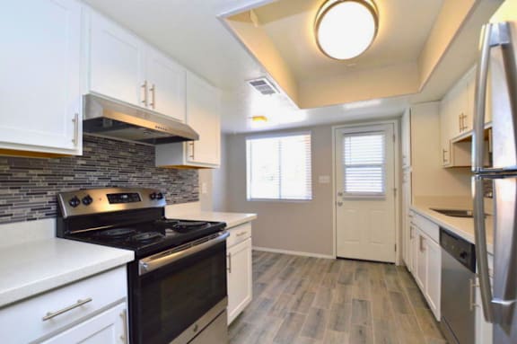 A kitchen with black and white appliances and wooden floors.