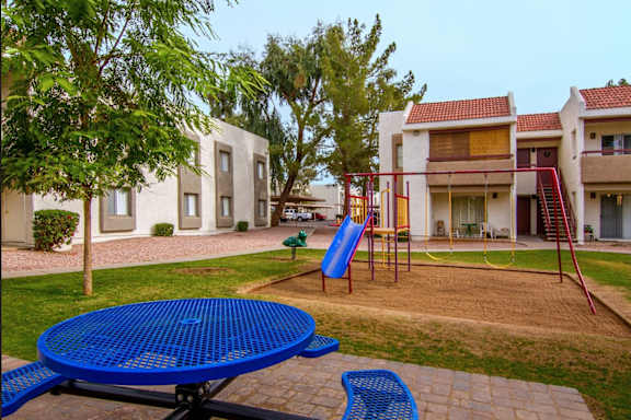 A playground with a blue slide and a blue table.