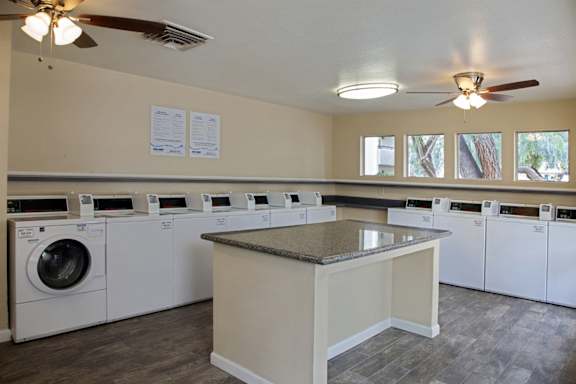 A laundry room with a row of washers and dryers.