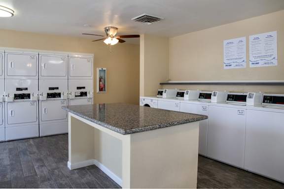 A laundry room with a row of washers and dryers.