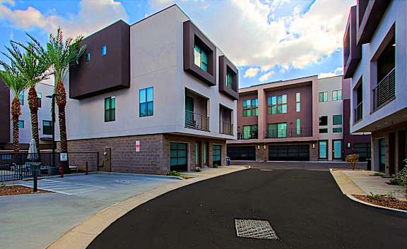 A modern building with a black driveway in front.