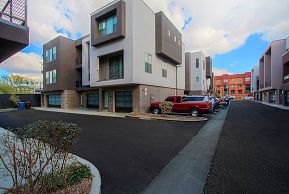 A modern apartment complex with a red car parked in front.