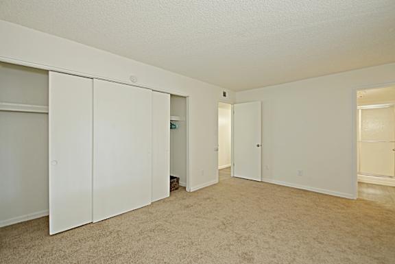 A room with white cupboards and carpeted floor.