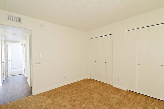 A room with white walls and brown carpet.