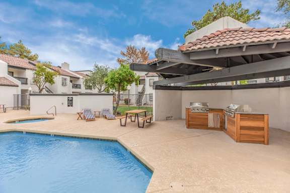 A pool with a table and chairs is surrounded by a building.