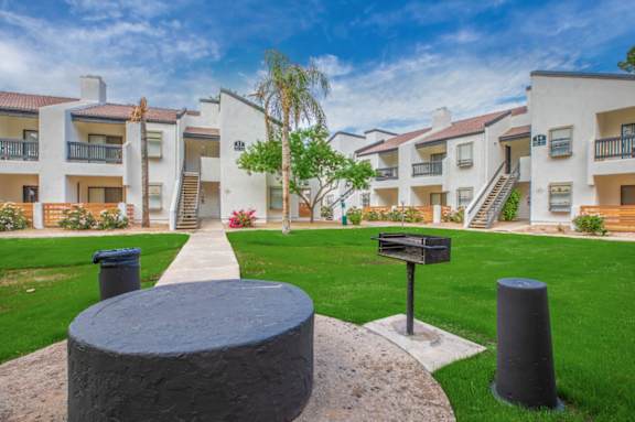 A modern apartment complex with a circular stone structure in the foreground.