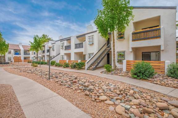 A modern apartment complex with a stone pathway leading to the entrance.