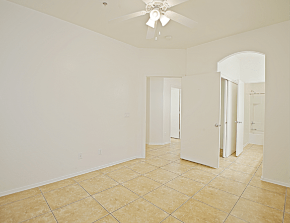 A room with a ceiling fan and tile flooring.