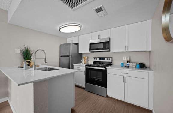 A modern kitchen with white cabinets and stainless steel appliances.