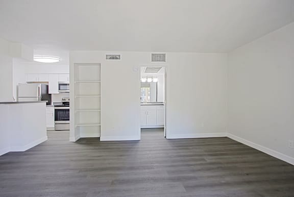 A kitchen with white cabinets and a refrigerator is visible through an open door.