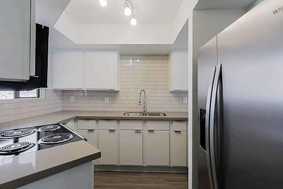 A modern kitchen with white cabinets and a stainless steel refrigerator.