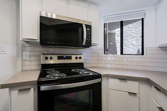 A modern kitchen with a black stove top oven and white cabinets.