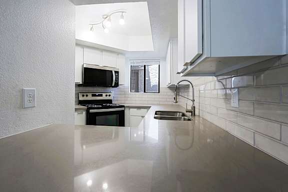 A modern kitchen with a large countertop and stainless steel appliances.