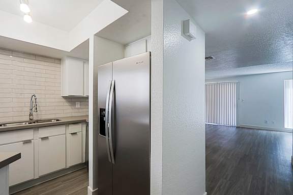 A modern kitchen with a stainless steel refrigerator and white cabinets.