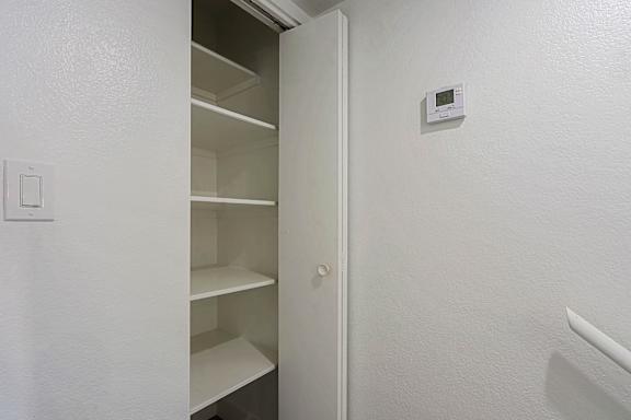 A white refrigerator with an open door and a small white box on the wall.