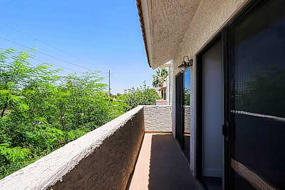 A balcony with a view of trees and a clear blue sky.