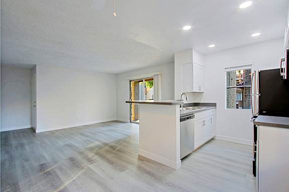 A kitchen with white cabinets and a wooden floor.