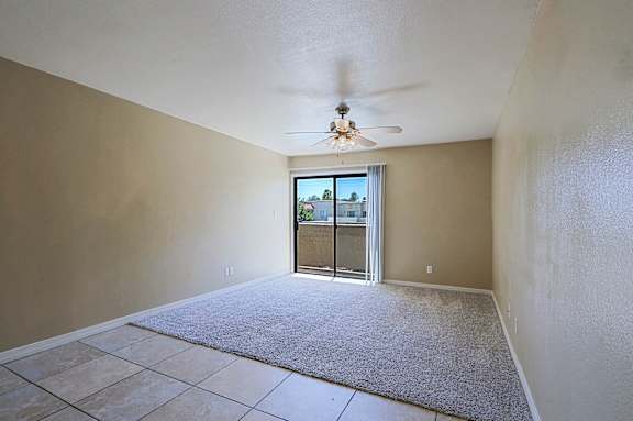 A room with a ceiling fan and a sliding glass door leading outside.